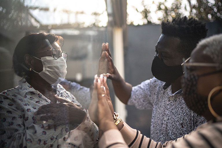 A group of masked people talking through a protective screen