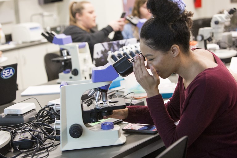 IUPUI undergrad research student using a microscope in one of the campus labs